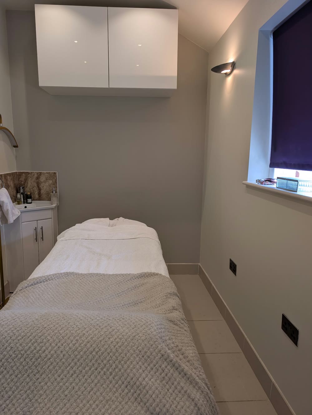 The Beauty Mill treatment room with a prepared treatment bed, soft lighting and calm grey walls